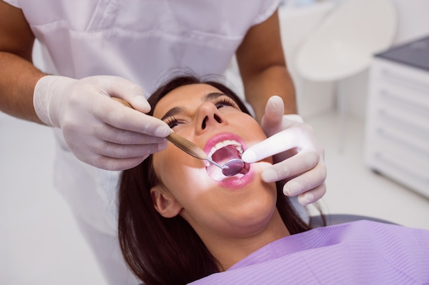 Dentista examinando os dentes do paciente com um espelho na boca Foto gratuita