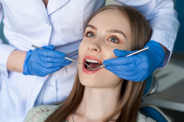 Dentista que examina os dentes de um paciente no dentista. Foto Premium