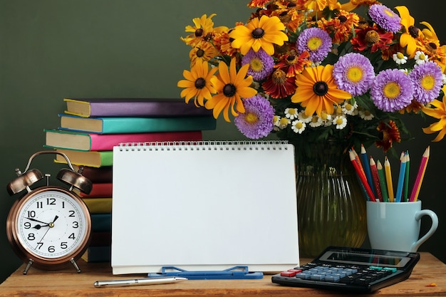 Dia do professor, 1º de setembro. para voltar para a escola. buquê de flores de outono, despertador e um álbum ao ar livre com uma espiral na base Foto Premium