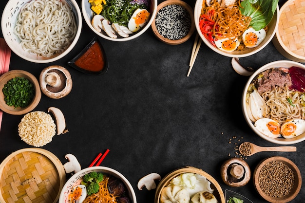 Diferentes tipos de macarrão com legumes em fundo preto, com espaço de cópia para escrever o texto Foto gratuita