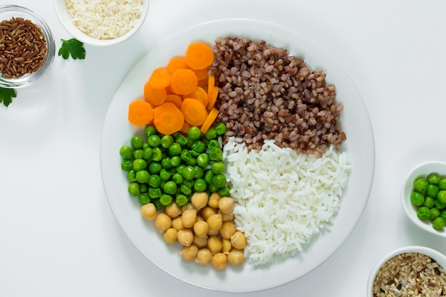 Diferentes tipos de mingau com legumes no prato com tigelas de arroz na mesa Foto gratuita