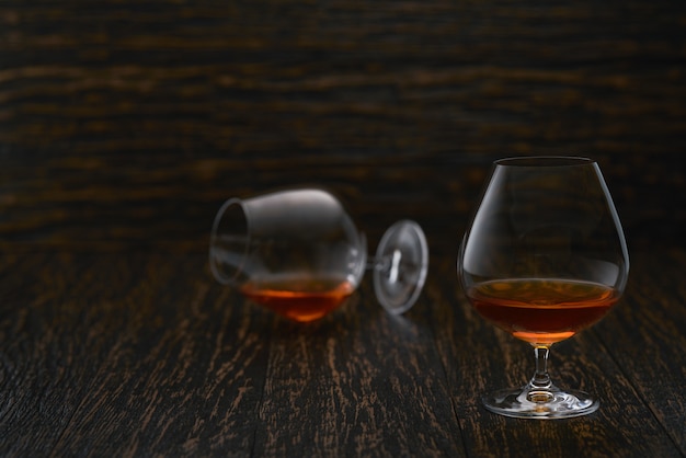 Dois copos de uísque ou uísque ou conhaque em uma mesa de madeira. Foto Premium