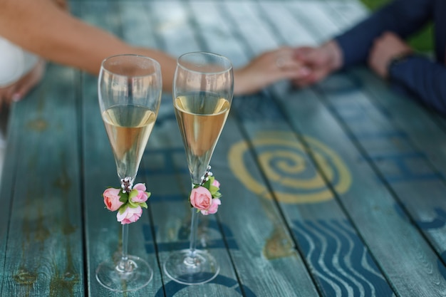 Dois copos decorados com champanhe em cima da mesa no dia do casamento. local de comemoração. Foto Premium
