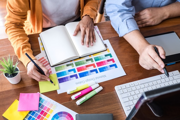 Dois criativos designer gráfico trabalhando na seleção de cores e amostras de cores, desenho em mesa digitalizadora Foto Premium