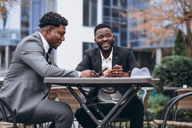 Dois empresário africano sentado fora café Foto gratuita