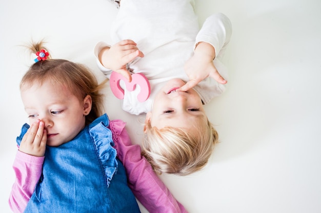 Duas Garotinhas Deitadas Juntas No Fundo Branco Foto Premium