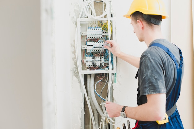 Eletricista que trabalha com painel de distribuição Foto gratuita