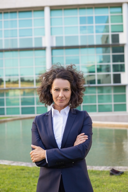 Empresária envelhecida média confiante posando perto de prédio de escritórios Foto gratuita