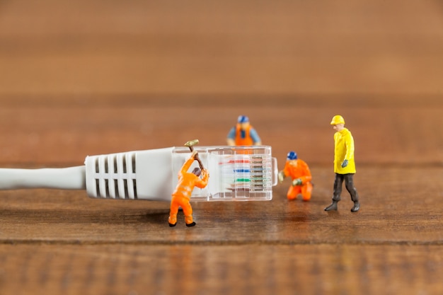 Engenheiro de miniatura e trabalhadores que trabalham com cabo lan Foto gratuita