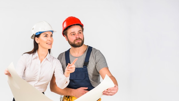 Engenheiro de mulher e construtor discutindo o projeto apontando para longe Foto gratuita