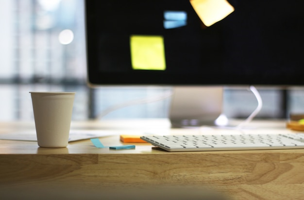 Escritório de mesa de mesa de madeira com tela de computador e xícara de café Foto Premium