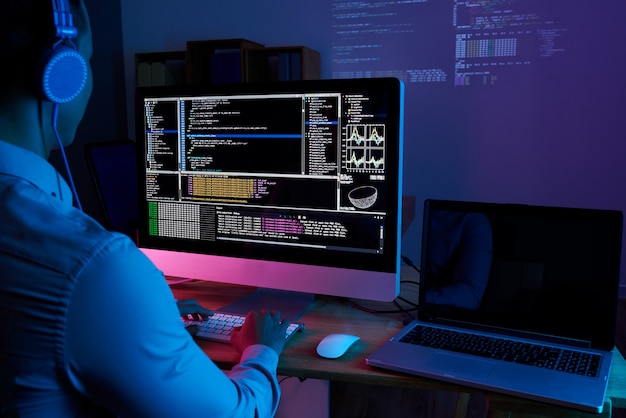 Especialista em ti, verificando o código no computador no escritório escuro à noite Foto gratuita