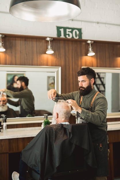 Estilista De Cabelo Fazendo O Corte De Cabelo Para O Cliente Na Barbearia Foto Gr Tis