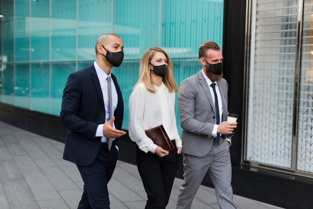 Executivos com máscaras médicas caminhando para o escritório Foto gratuita