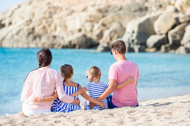Família bonita feliz com as crianças caminhando juntos na praia tropical durante as férias de verão Foto Premium