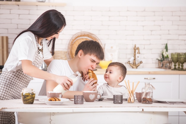 Família feliz tomando café juntos família jovem comendo à mesa na