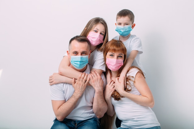 Família jovem em máscaras médicas durante a quarentena em casa. Foto Premium