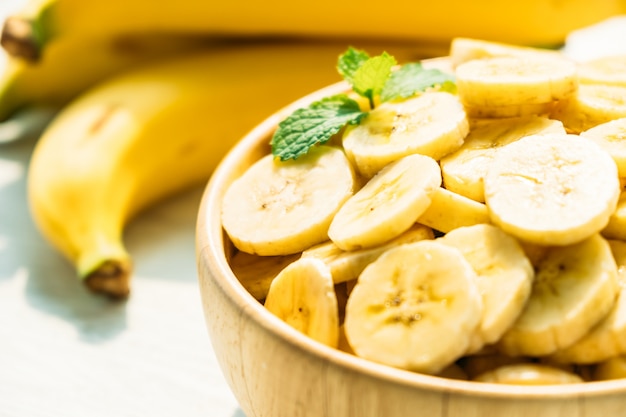 Fatias de banana amarela crua na tigela de madeira Foto Grátis