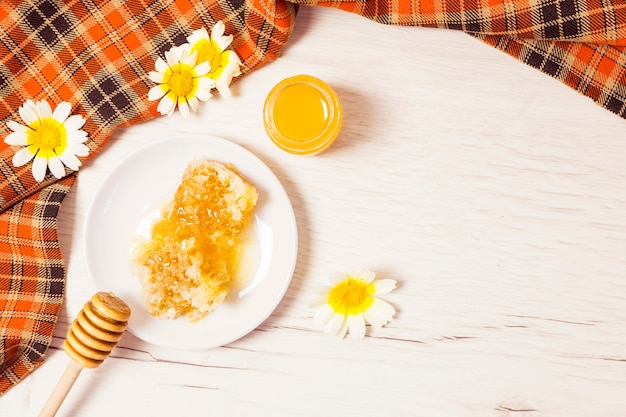 Favo de mel e mel com toalha de mesa quadriculada na mesa de madeira Foto gratuita