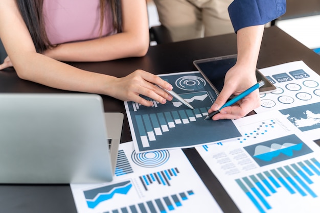 Fechar a mão do funcionário gerente de marketing, apontando para o documento de negócios durante a discussão na sala de reuniões, caderno na mesa de madeira - conceito de negócio Foto gratuita