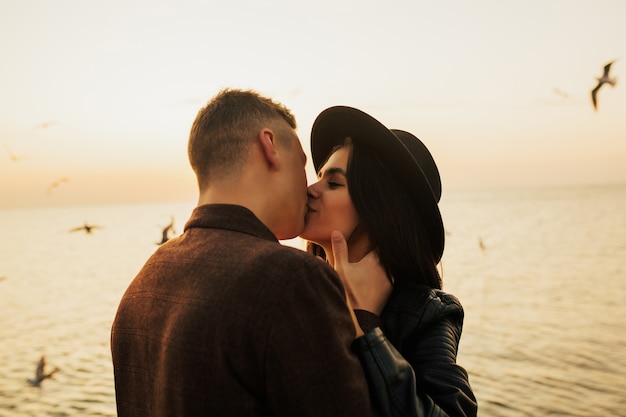 Feche O Retrato De Um Lindo Casal Jovem Elegante Apaixonado Em Pé E Beijando Na Praia Ao Pôr Do 5494