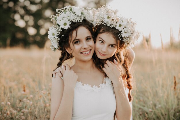 Feliz mãe e filha sorrindo e abraçando na grama no campo no verão Foto Premium