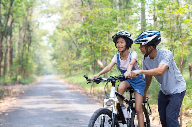 Feliz pai e filha de bicicleta no parque Foto Premium