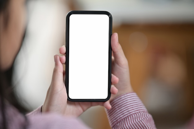 Feminino mão segurando o celular de tela branca em branco sobre fundo desfocado bokeh Foto Premium