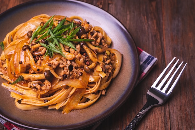 Fettuccine frite com molho de pimenta sichuan chinês com carne de porco, cogumelos e cebola Foto Premium