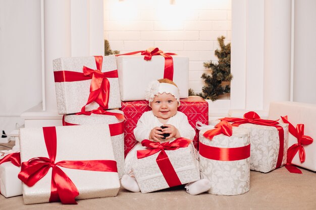 Filho bonito vestido branco posando debaixo da árvore de natal. Foto Premium