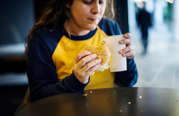 Fim, cima, adolescente, menina, comer, hambúrguer, obesidade, conceito Foto gratuita