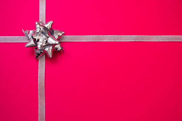 Fitas de prata com curva no fundo vermelho. conceito de presente de natal. vendas Foto Premium