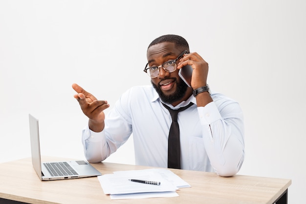 Focada gerente de escritório afro-americano sentado no escritório com laptop, lendo documentos importantes com expressão confusa e segurando a cabeça com a mão Foto Premium