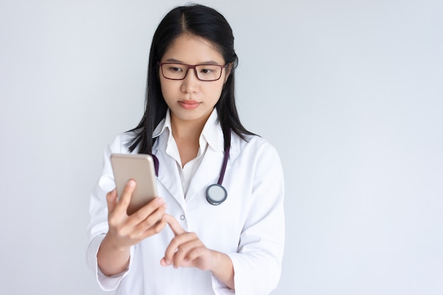 Focada jovem médico feminino usando smartphone Foto gratuita