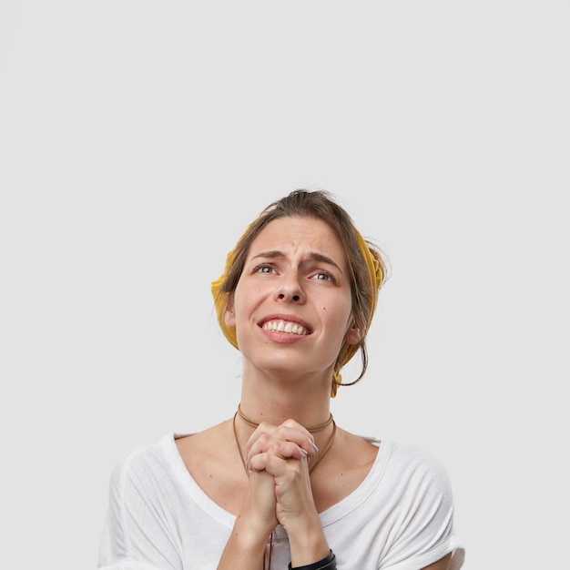 Foto de estúdio de uma mulher européia de mãos dadas orando sobre o