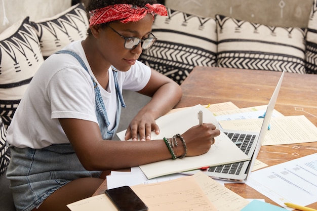 na imagem uma estudante ocupada estudando utilizando papéis e o computador | O guia do servidor público de como se organizar financeiramente