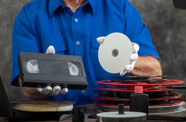 Fotógrafo de mão segurando a fita vhs e dvd para conversão Foto Premium