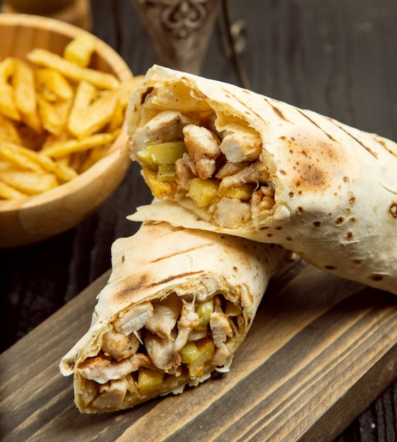 Frango durum, shaurma com lavash e batatas fritas na placa de madeira Foto gratuita