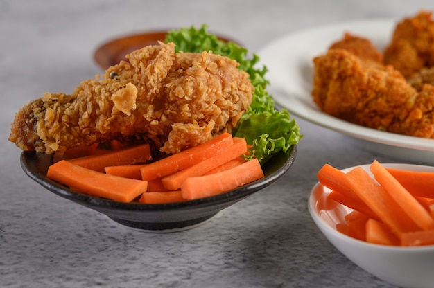 Frango frito crocante em um prato com salada e cenoura Foto gratuita