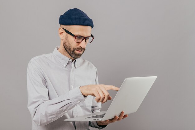 Freelancer masculino faz o trabalho do projeto, pontos com o dedo indicador na tela do computador portátil Foto Premium
