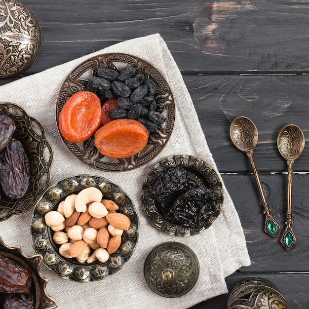 Frutos e nozes secos; datas para ramadan com colheres sobre a mesa de madeira Foto gratuita