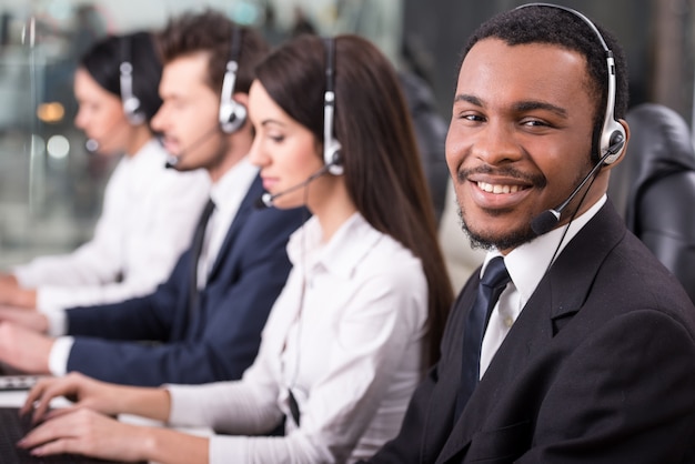 Funcionários do call center estão sorrindo e trabalhando em computadores. Foto Premium