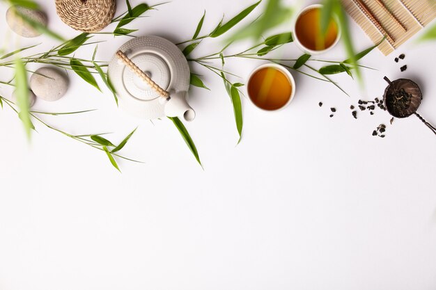 Fundo de comida asiática com chá verde, xícaras e bule com galhos de bambu Foto Premium