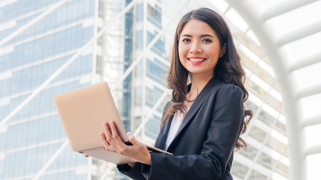 Garota de negócios com computador notebook e cidade de fundo. Foto Premium
