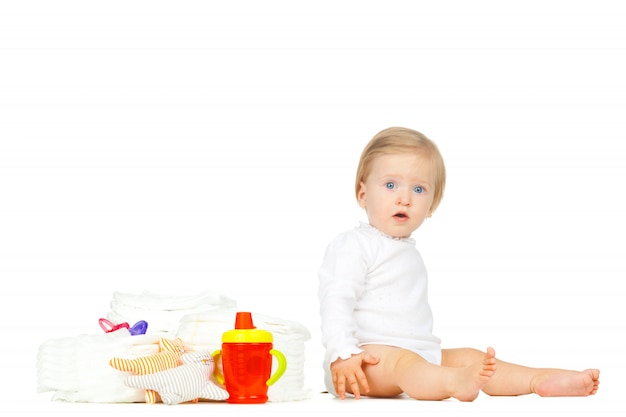 Garoto branco com fraldas empilhadas e brinquedos isolados no branco Foto Premium