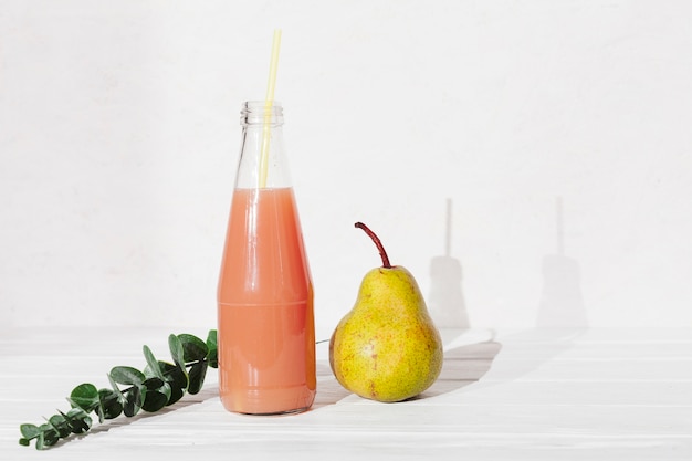Garrafa de suco com pêra e folhas Foto gratuita