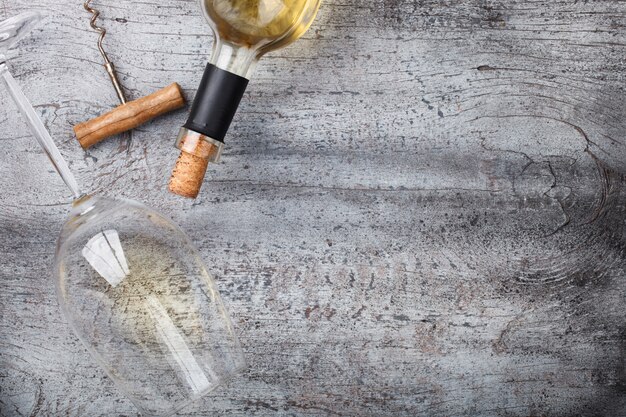 Garrafa de vinho branco, um saca-rolhas, um copo Foto Premium
