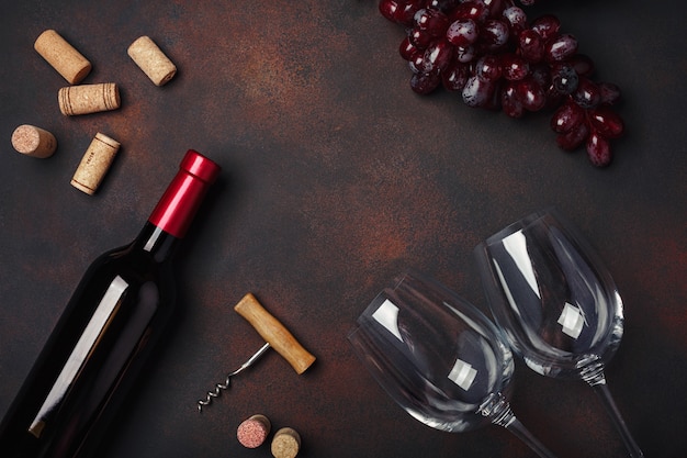 Garrafa de vinho, dois copos, saca-rolhas e rolhas, no fundo enferrujado com copyspace, vista superior Foto Premium