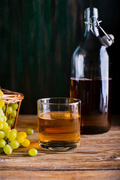 Garrafa e copo na mesa com suco de uvas frescas Foto gratuita