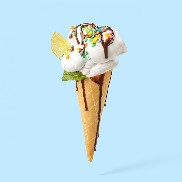 Gelado em um chifre com cobertura do cal, da hortelã e do chocolate em um fundo azul. Foto Premium